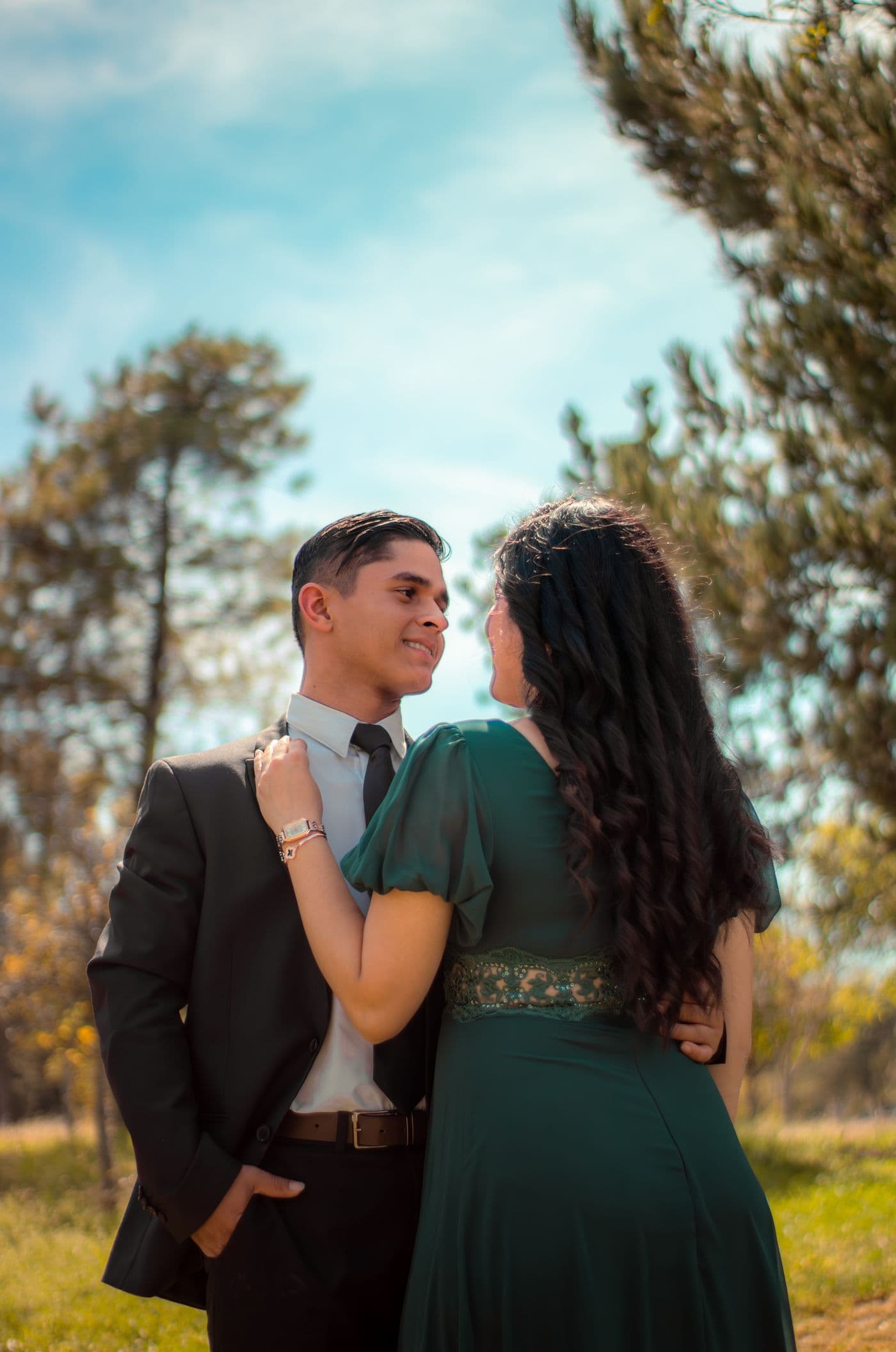 A couple in a dark suit and emerald dress in a sunlit garden